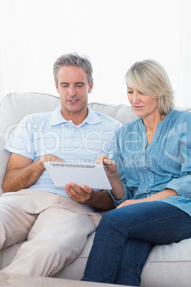 Couple using tablet pc together on the sofa