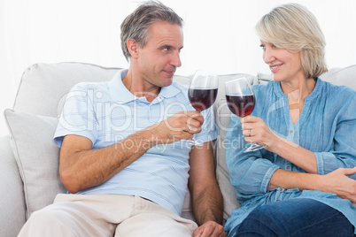 Couple toasting with red wine on the sofa