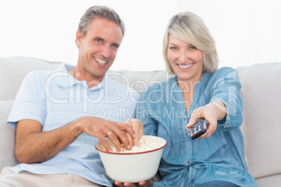 Couple watching tv and eating popcorn on the couch