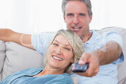 Cheerful couple relaxing at home watching tv