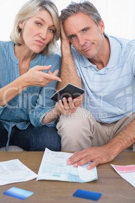 Anxious couple going over their debt looking at camera