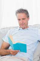 Man relaxing on his sofa with a book