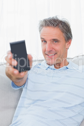 Man showing smartphone to camera and smiling