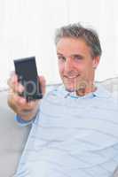 Man showing smartphone to camera and smiling