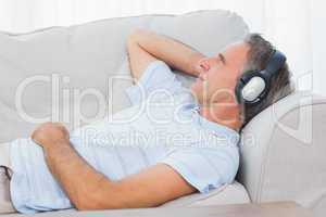 Man lying on couch listening to music