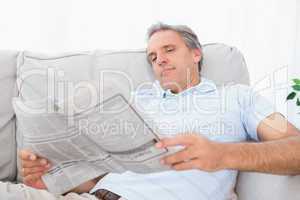 Man reading the newspaper on couch