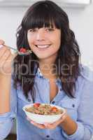 Pretty brunette having bowl of cereal and fruit