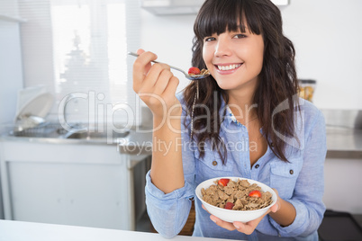 Attractive brunette eating bowl of cereal and fruit