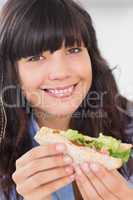 Cheerful brunette having a salad sandwich
