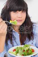 Happy brunette having a salad for lunch