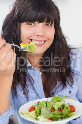 Smiling brunette having a salad for lunch