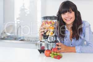 Happy brunette with juicer full of fruit