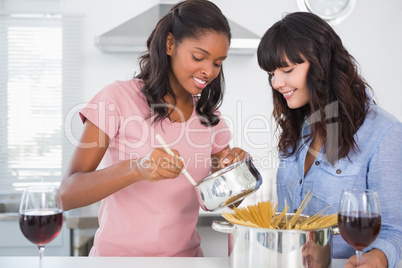 Cheerful friends preparing spaghetti dinner together