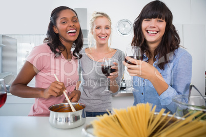 Laughing friends making spaghetti dinner together and drinking r