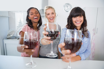 Cheerful friends toasting to the camera with glasses of red wine