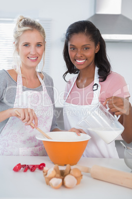 Smiling friends making dough together looking at camera