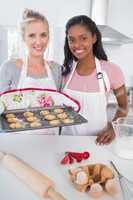 Smiling woman showing freshly baked cookies with friend