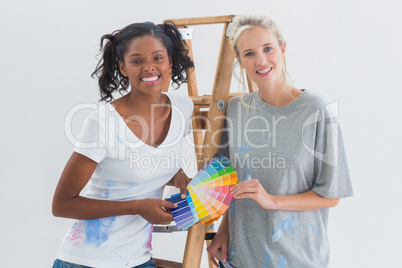Friendly housemates choosing colour for wall looking at camera