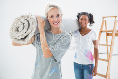 Smiling housemates carrying rolled up rug