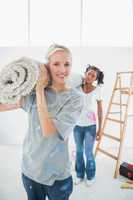 Cheerful housemates carrying rolled up rug in new home