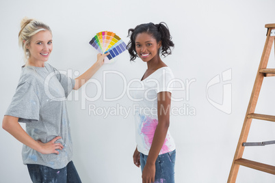 Housemates picking colour for blank wall and smiling at camera