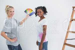 Housemates picking colour for blank wall and smiling at camera