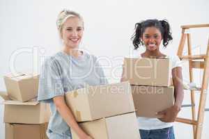 Cheerful housemates carrying moving boxes