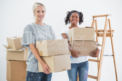 Happy housemates carrying moving boxes