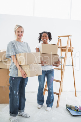 Pretty young housemates carrying moving boxes