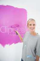 Happy blonde painting her wall pink