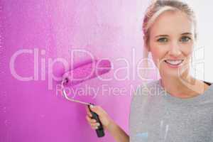 Cheerful blonde painting her wall pink