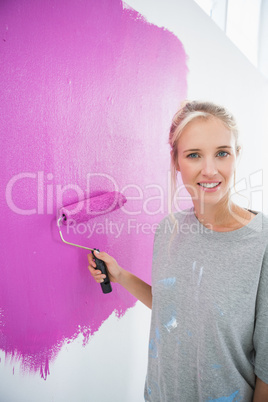 Pretty woman painting her wall pink