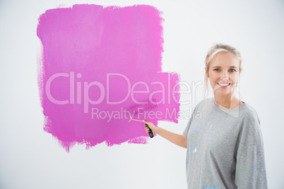 Happy young woman painting her wall pink