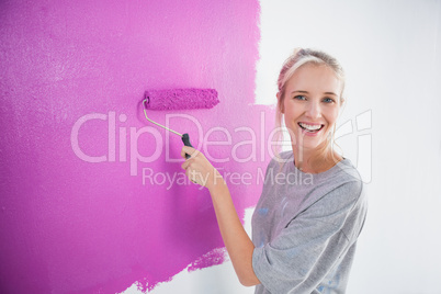 Laughing woman painting her wall in pink