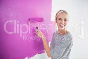 Laughing woman painting her wall in pink