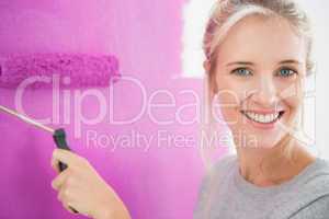Smiling woman painting her wall in pink