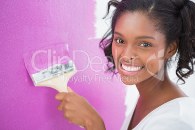 Smiling young woman painting her wall in pink
