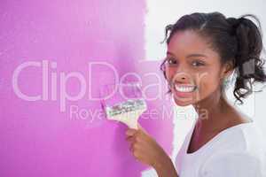 Happy young woman painting her wall in pink