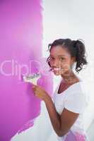 Cheerful young woman painting her wall in pink
