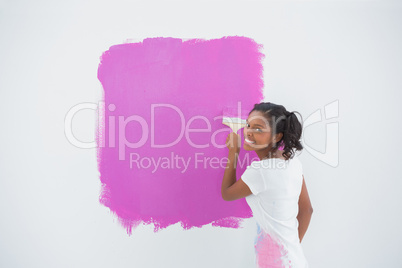 Smiling woman painting her wall in bright pink