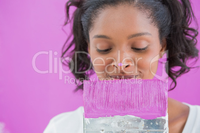 Cheerful woman holding paintbrush with paint on her nose