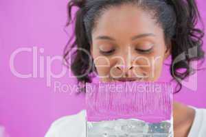 Cheerful woman holding paintbrush with paint on her nose