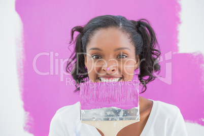Young woman holding paintbrush with paint on her nose