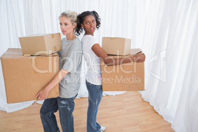 Friends standing back to back holding moving boxes
