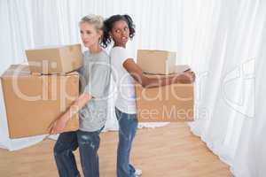 Friends standing back to back holding moving boxes