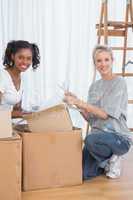 Cheerful friends unpacking boxes in new home