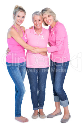 Cheerful women wearing pink tops and ribbons for breast cancer