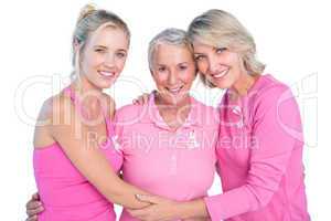 Embracing women wearing pink tops and ribbons for breast cancer