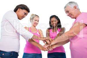 Smiling women wearing breast cancer ribbons putting hands togeth