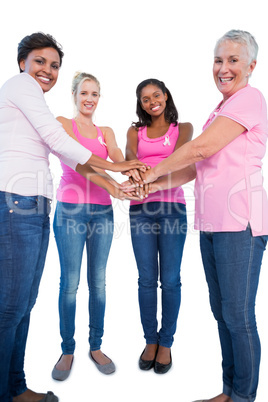 Happy women wearing breast cancer ribbons putting hands together